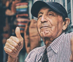 Old man agrees with something by putting his thumb up.