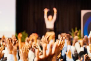 Man with his arms in the air looking at crowd also with arms in the air.