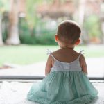 Toddler in a dress sitting outside on a playground