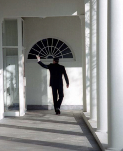 A man walking and waving his left hand at someone